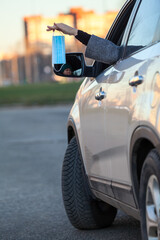 Naklejka premium Woman holding new medical mask in hand, stretching her hand through a car window