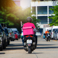 The back of a motorcyclist delivers food in a pink dress form, a pink food bag is rushing to deliver to customers online.