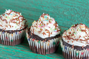 Delicious homemade cupcakes on a green wooden table and background. Holiday food