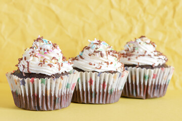Delicious homemade cupcakes on a yellow crumpled paper background. Holiday food