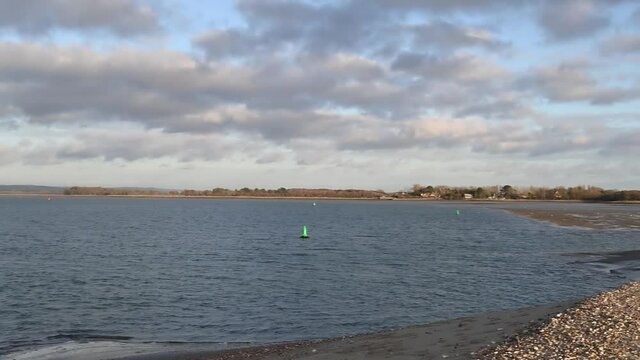 Estuary at East Head near West Wittering with a sailing boat turning and maneuvering. 