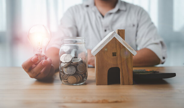 saving energy and money concept. idea for save or investment. businessman holding lightbulb on coins stacking on desk with calculator.
