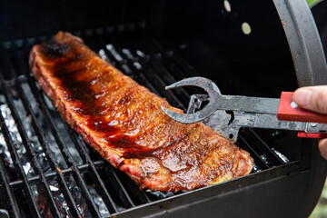 Close-up Of BBQ Roast and Smoked Pork Spareribs glazed with sauze On The Hot Charcoal Grill With Flames, Barbecue and hobby concept