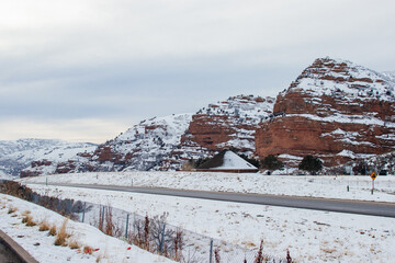 High red mountains near the highway are covered with snow. Winter mountain landscape by the road. Echo Canyon, Utah, USA