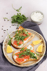 Salmon sandwich with cream cheese and arugula on marble table. top view