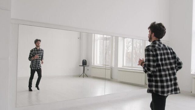 Young handsome man dancing ballroom dancing. A professional ballroom dancer trains in a large white hall.