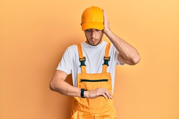 Hispanic young man wearing handyman uniform looking at the watch time worried, afraid of getting late