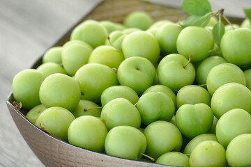 green fresh sour plums and large quantities in the plate,