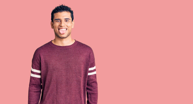 Hispanic handsome young man wearing casual clothes sticking tongue out happy with funny expression. emotion concept.
