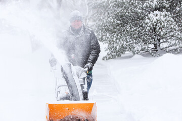 Man using a snowblower to clear his sidewalk and driveway