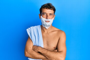 Handsome man saving beard with shave foam over face skeptic and nervous, disapproving expression on...