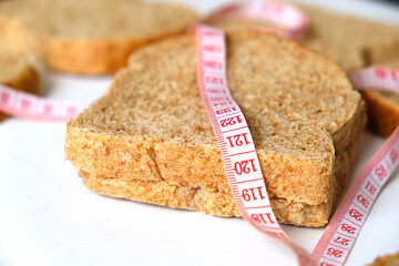 Against excessive weight gain at home, bran bread, slices of bran bread and a tape measure,