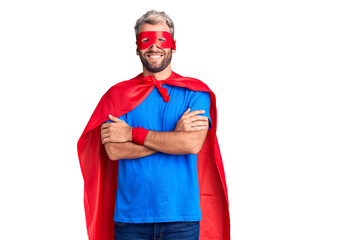 Young blond man wearing super hero custome happy face smiling with crossed arms looking at the camera. positive person.