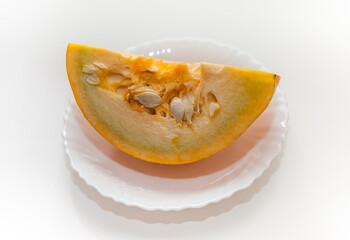 A piece of pumpkin in close-up on a white ceramic plate on a white background. Focus in the center