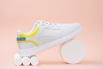 new trendy white sports sneaker on a stand on a pink background