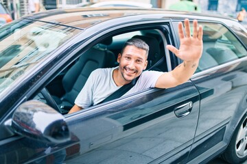 Young hispanic man smiling happy sitting on the car.