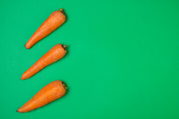 Carrots on a green background. Healthy eating. Three carrots lie next to each other. There is a place for an inscription or logo