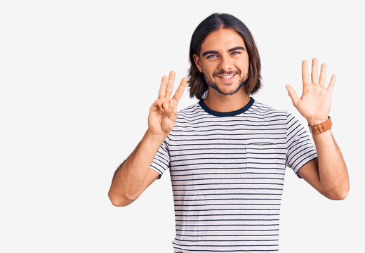 Young handsome man wearing casual clothes showing and pointing up with fingers number eight while smiling confident and happy.