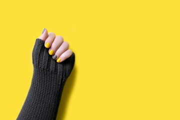 Detail of womans hand wearing gray sweater with manicure