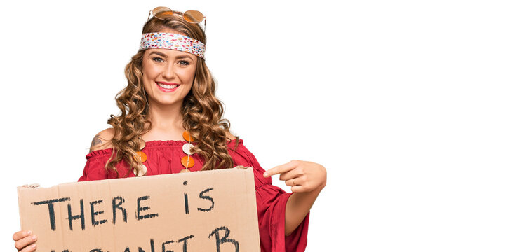 Young blonde girl wearing hippie style holding there is no planet b banner smiling happy pointing with hand and finger