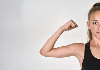 Obraz premium Cropped shot of cute sportive girl child in sportswear looking at camera, showing biceps while posing isolated over white background