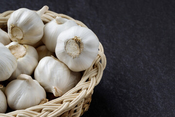 Garlic Cloves and Bulb in vintage organic woven basket on wooden background. spice is an herb that is grown around the world.