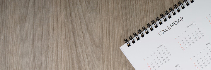 close up top view calendar month schedule to make appointment meeting or manage timetable each day lay on wooden background for planning work and travel concept. banner copy space.