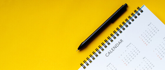 A pen with calendar on yellow background  - obrazy, fototapety, plakaty