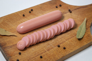 Sausages on a wooden board. A chopped sausage next to a whole sausage. meat product on a white background.