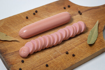 Sausages on a wooden board. A chopped sausage next to a whole sausage. meat product on a white...