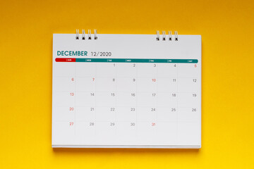 close up top view calendar 2020 month december end of the year schedule to make appointment meeting or manage timetable each day lay on yellow background for planning work and travel concept.