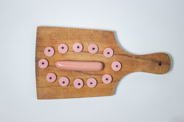 Sausages on a wooden board. Sliced sausage around a whole sausage. meat product on a white background.