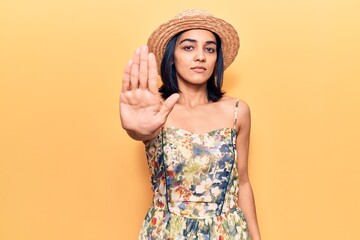 Young beautiful latin woman wearing summer hat doing stop sing with palm of the hand. warning...