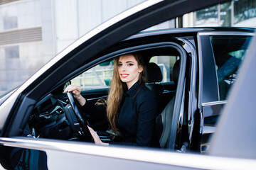 Young businesswoman in black wear with a expensive car