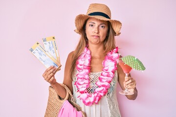 Middle age hispanic woman wearing hawaiian lei holding boarding pass and cocktail skeptic and nervous, frowning upset because of problem. negative person.