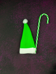 Christmas dark background. Green cap of Santa Claus.
