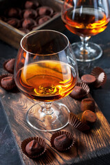Whiskey or cognac  in  glass with  truffles candy on  dark background
