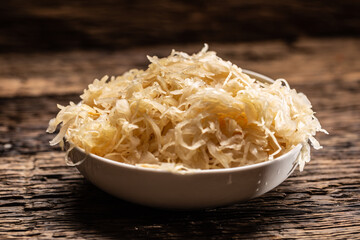 A bowl full of raw sauerkraut cabbage pickle on a rustic dark surface