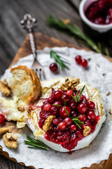 Baked cheese Camembert with cranberries and nuts. rosemary and baguette bread. European cuisine
