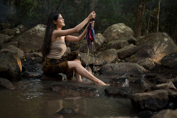 Portrait Asian young woman washing clothes at the stream.Beautiful Village women sitting and washing the clothes at the river.Countryside life style concept.