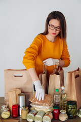 woman in medical gloves packing food for donation
