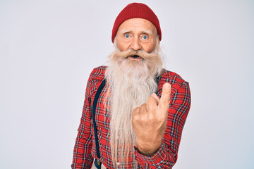 Old senior man with grey hair and long beard wearing hipster look with wool cap beckoning come here gesture with hand inviting welcoming happy and smiling