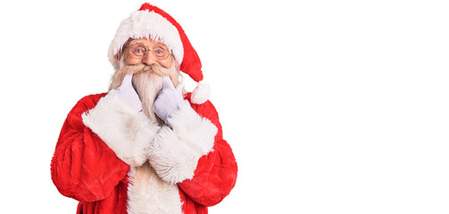 Old senior man with grey hair and long beard wearing traditional santa claus costume smiling with open mouth, fingers pointing and forcing cheerful smile