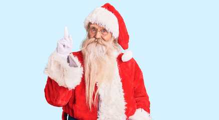 Old senior man with grey hair and long beard wearing traditional santa claus costume pointing finger up with successful idea. exited and happy. number one.