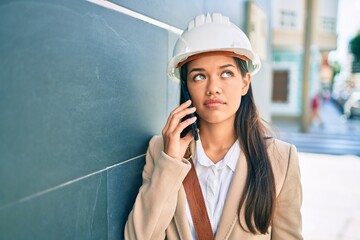 Young latin architect girl with serious expression talking on the smartphone at the city.