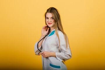 Portrait of woman doctor with stethoscope looking at camera on yellow background