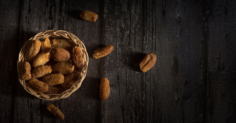 Dried dates in basket on a dark wooden background