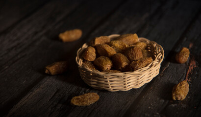 Dried dates in basket on a dark wooden background