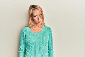 Beautiful blonde woman wearing casual winter sweater skeptic and nervous, frowning upset because of...
