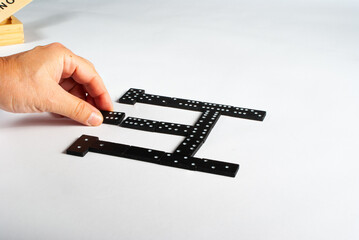 Man's hand placing domino piece on white background